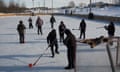 a group of young people stand on ice and play broomball outside