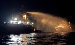 Water is fired from a tug vessel on to ship in sea