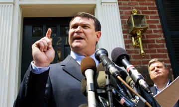 a man in a suit speaks into a bunch of microphones