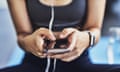 Closeup shot of a sporty woman using a cellphone while exercising in a studio