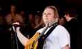 Lewis Capaldi in white T-shirt with acoustic guitar around his neck on stage at Glastonbury