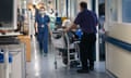 Staff and an elderly patient in a wheelchair on an NHS hospital ward