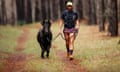 A runner runs with a black pony in a forest