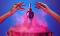 A woman's hands around a perfume bottle above a smoke billowing cauldron