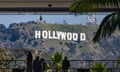 people stand by barricade overlooking hollywood sign