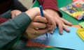 A teaching assistant helps a Send pupil learn to write with a pen and stencil