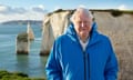 David Attenborough standing in front of white cliffs on the coast
