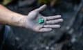 An emerald held out in the palm of a muddy hand