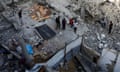 Palestinians stand amid rubble at the site of an Israeli airstrike on a house in Khan Younis