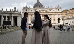 Two nuns and a man speak outside St. Peter's Basilica in Rome
