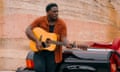 Kashus Culpepper holds a guitar, resting against a car
