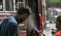 A volunteer sprays water on a passerby's face to cool him off on an unusually hot April day in Karachi, Pakistan