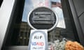 Flowers next to a homemade sign saying RIP USAid, 1961-2025 laid outside the door of the USAid building